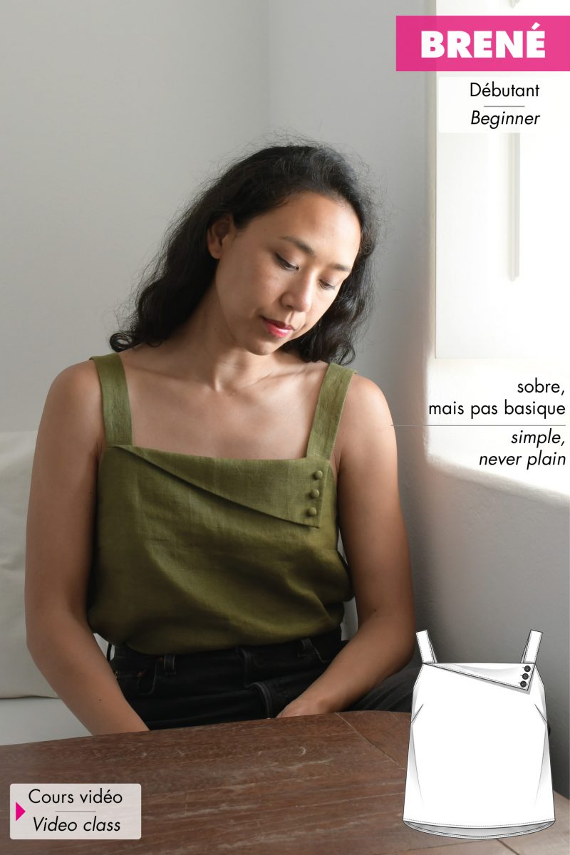 Femme aux cheveux noirs assise devant une fenêtre portant un haut à bretelles en lin couleur vert olive